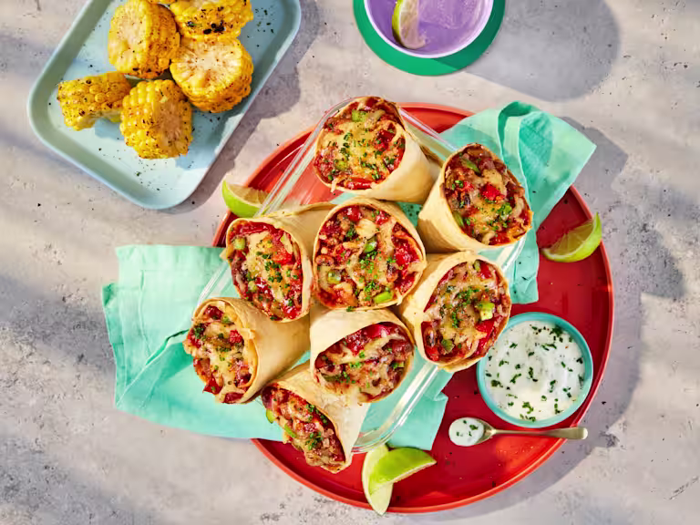 Tortilla cones filled with Quorn Mince, black-eyed beans and peppers in a tomato sauce, topped with mozzarella cheese. Served on a plate with a yoghurt and chive dip.