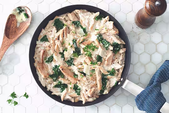 Gluten free recipe of Pasta Alfredo made with Quorn Roast Mini Fillets and penne pasta topped with kale served in a saucepan