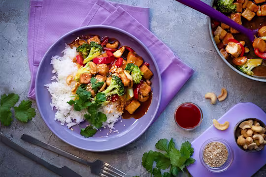 Lautasellinen Sticky Quorn Kuutioita makean tulisessa sriracha- ja limekastikkeessa. Päällä parsakaalia ja punaista paprikaa. Tarjoillaan riisin kera.