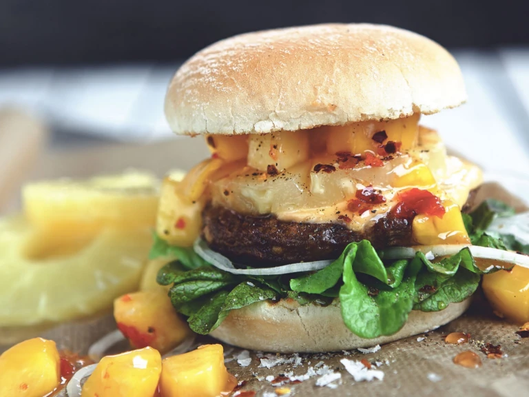 Veggie burger recipe made with Quorn Quarter Pounders on top of lettuce garnished with onions, pineapple and mango salsa in a bun