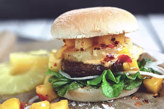 Veggie burger recipe made with Quorn Quarter Pounders on top of lettuce garnished with onions, pineapple and mango salsa in a bun