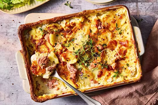 Vegetarian gratin with Quorn Ham Roast in a serving dish with serving spoon.