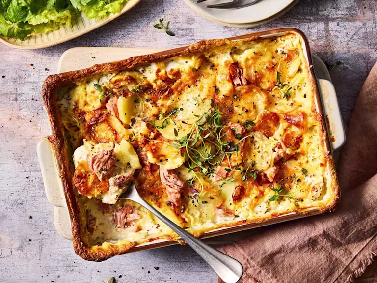 Vegetarian gratin with Quorn Ham Roast in a serving dish with serving spoon.