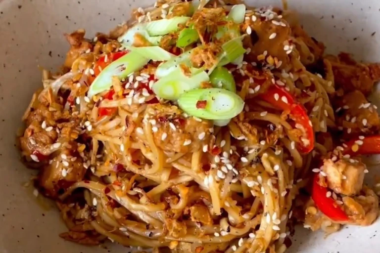 Sweet chilli noodles with Quorn Vegetarian Chicken pieces, red pepper, onions and beansprouts in a bowl garnished with spring onion and sesame seeds. 
