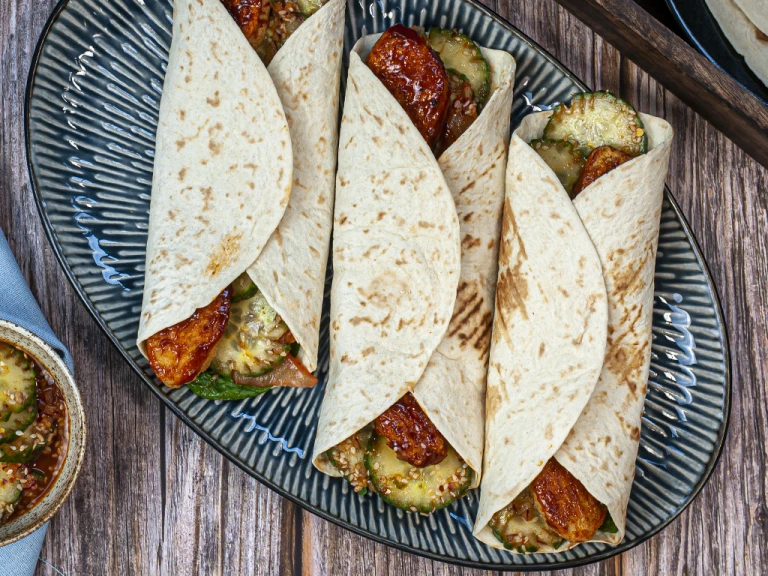 Three Korean wraps served on a blue dish.