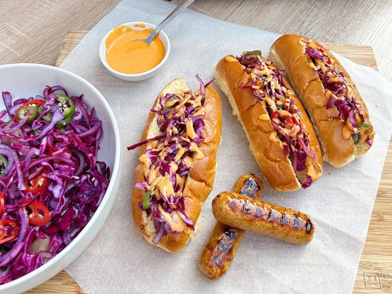 Three sticky Asian-style vegetarian hot dogs with a side of slaw and two Quorn Sausages on display.