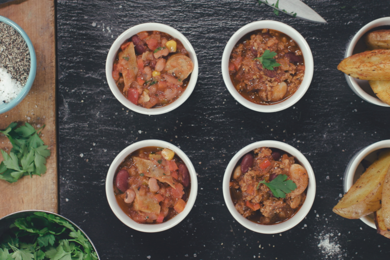 Vegetarian Mexican Chilli made with Quorn Sausages and beans served in 4 individual pots on top of a black slate