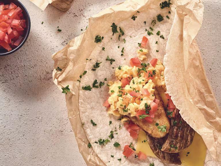 Quorn Vegetarian Breakfast Wrap opened to show Quorn Sausage Patties, scrambled eggs and chopped tomatoes.