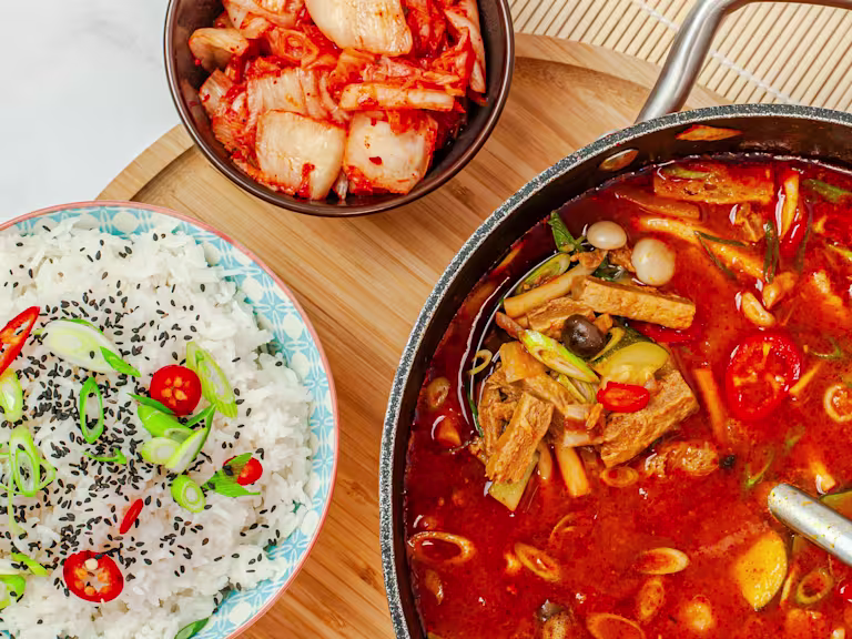 Korean Doenjang Jigae using Quorn Steak Strips in a bowl with a bowl of rice on the side.