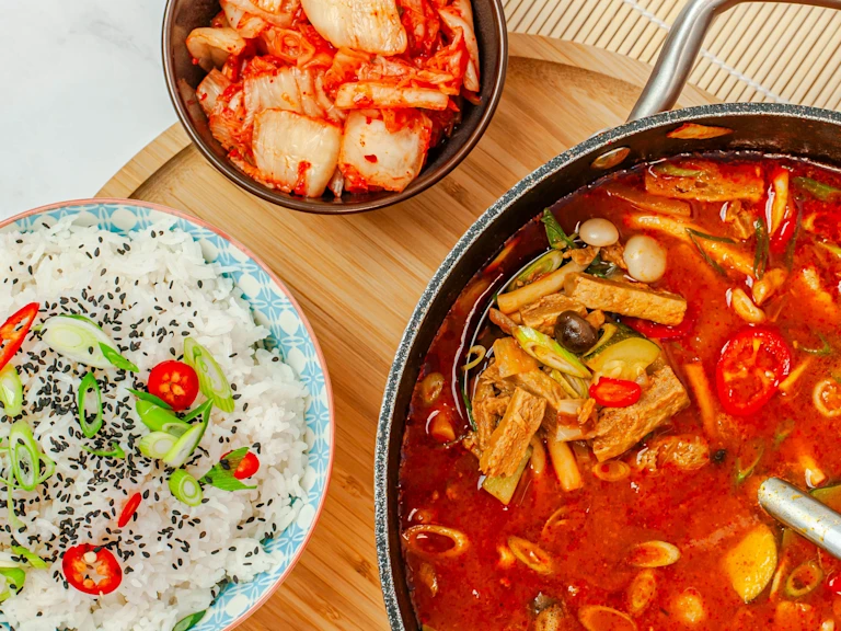 Korean Doenjang Jigae using Quorn Steak Strips in a bowl with a bowl of rice on the side.