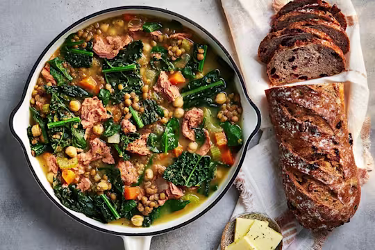 Ham and lentil soup with Quorn pieces in a bowl with a bread roll on the side