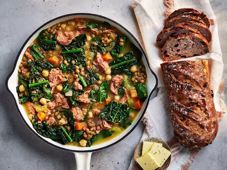Ham and lentil soup with Quorn pieces in a bowl with a bread roll on the side