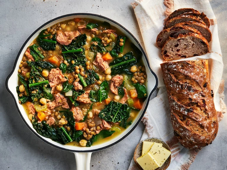 Ham and lentil soup with Quorn pieces in a bowl with a bread roll on the side