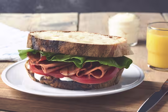 A BLT sandwich on rustic white bread with mayonnaise, lettuce, sliced tomatoes, and grilled Quorn Vegetarian Bacon Slices.