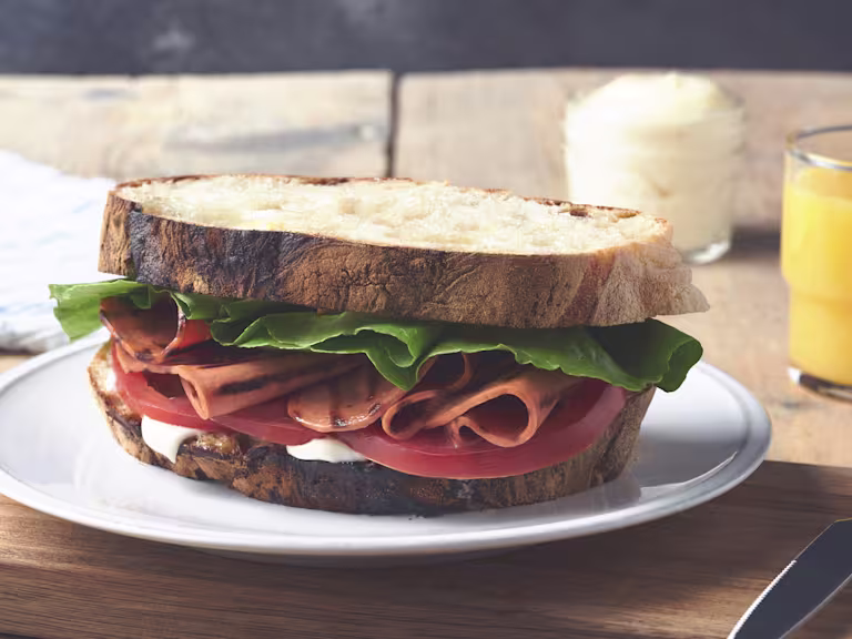 A BLT sandwich on rustic white bread with mayonnaise, lettuce, sliced tomatoes, and grilled Quorn Vegetarian Bacon Slices.