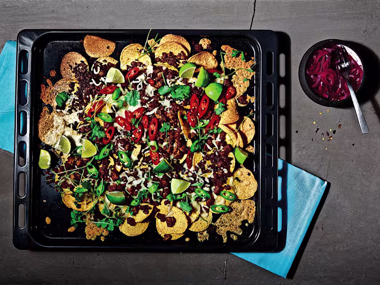 A platter of vegetarian loaded nachos with dip on the side.