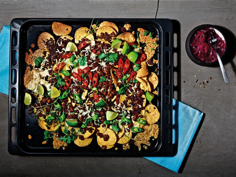 A platter of vegetarian loaded nachos with dip on the side. 