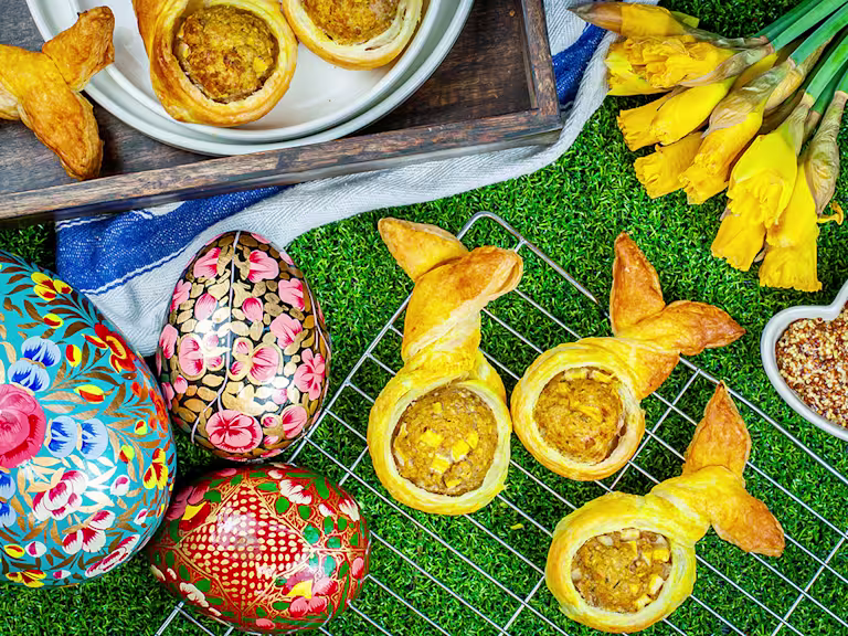 Vegan bunny rolls served on a cooling rack with easter eggs and daffodils on the side.