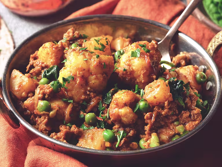 A serving bowl containing a recipe of Easy Quorn Mince & Madras Curry sat beside two servings of chapatti bread.
