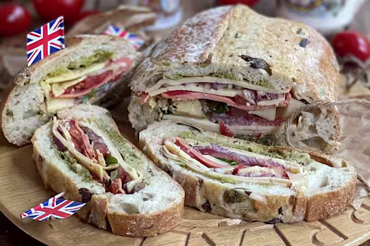 Stuffed picnic loaf sliced served on a wooden board.