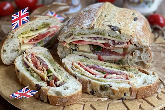 Stuffed picnic loaf sliced served on a wooden board.