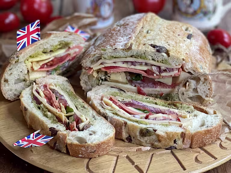 Stuffed picnic loaf sliced served on a wooden board.
