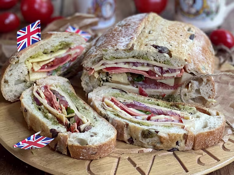 Stuffed picnic loaf sliced served on a wooden board.