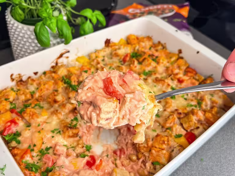 En ugnsform med krämig vegetarisk risgratäng, toppad med Quorn Bitar, paprika och jordnötter