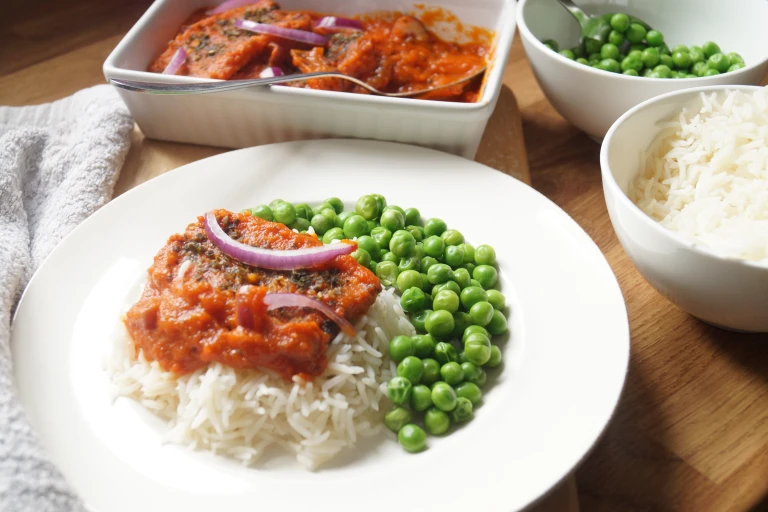 Vegan Nigerian fish stew made with Quorn Vegan Fishless Fingers served atop rice with peas on the side.