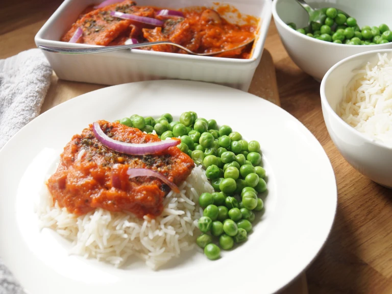 Vegan Nigerian fish stew made with Quorn Vegan Fishless Fingers served atop rice with peas on the side.