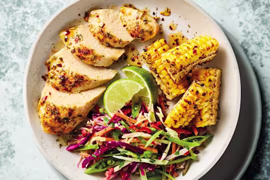 Quorn Fillets med het honung, majs, limeklyftor och kålsallad på en grå tallrik.