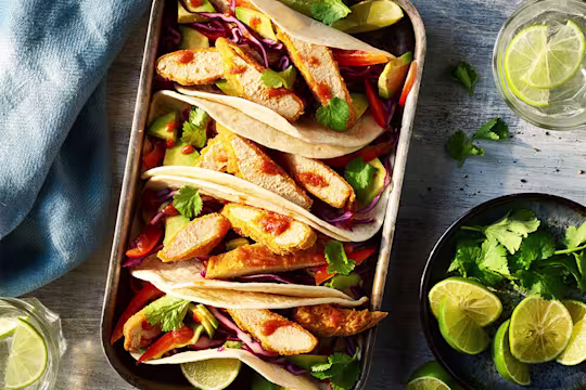 4 Quorn Vegan Buffalo Tacos served alongside slices of lime.