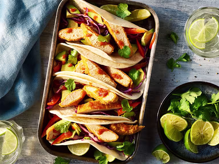 4 Quorn Vegan Buffalo Tacos served alongside slices of lime.