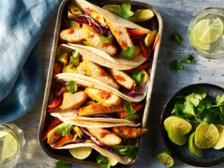 4 Quorn Vegan Buffalo Tacos served alongside slices of lime.