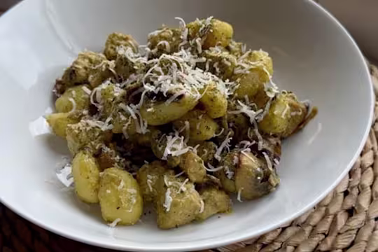 Creamy pesto gnocchi with Quorn Pieces in a bowl topped with parmesan cheese.