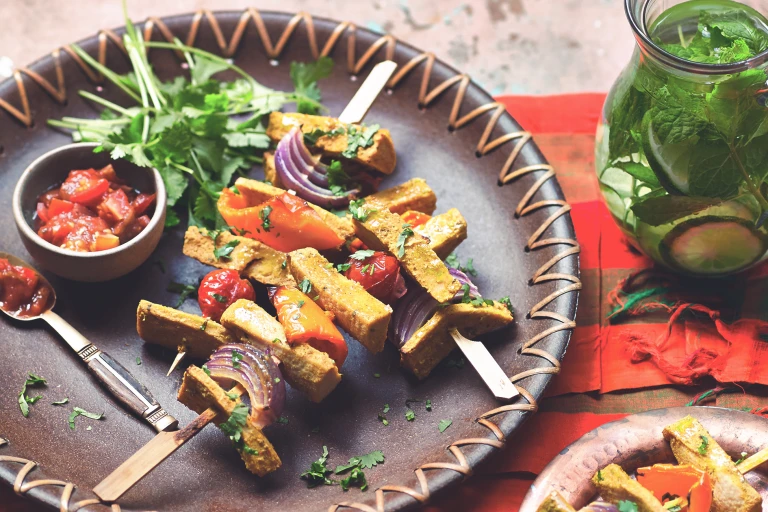 Vegetarian skewers made with Quorn Vegetarian Fillets, peppers, tomatoes and onion served on a plate with a side of tomato salsa