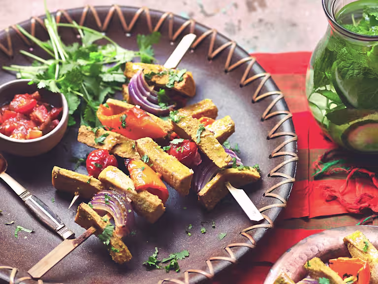 Vegetarian skewers made with Quorn Vegetarian Fillets, peppers, tomatoes and onion served on a plate with a side of tomato salsa