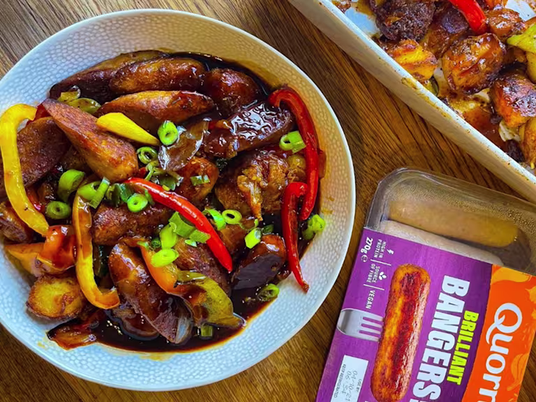 Potato bake served in a bowl positioned next to Quorn Brilliant Bangers vegan sausages