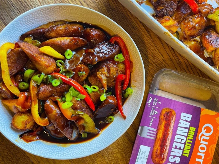 Potato bake served in a bowl positioned next to Quorn Brilliant Bangers vegan sausages