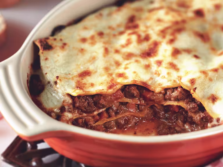 Gluten free lasagne made with Quorn Mince layered between gluten free pasta sheets served in a red ceramic dish