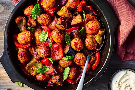 One pot harissa Quorn meatballs served in a black dish with crème fraiche on the side.