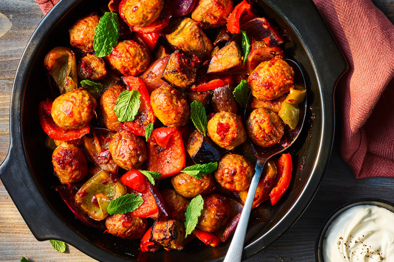 One pot harissa Quorn meatballs served in a black dish with crème fraiche on the side.