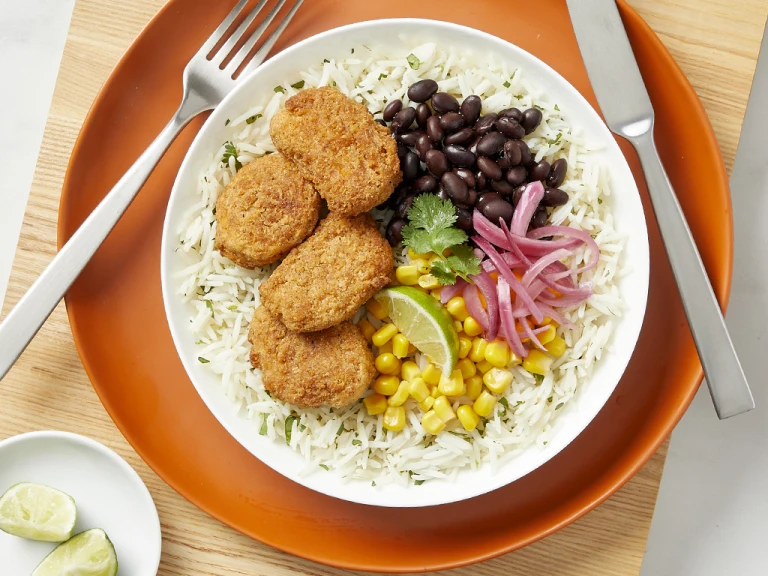 Quorn meatless dippers served on a bed of white rice with vegetables on the side.