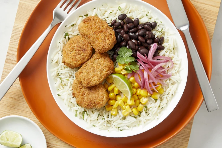 Quorn meatless dippers served on a bed of white rice with vegetables on the side.