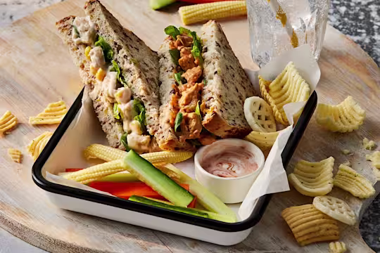 Two sandwiches, one Quorn Vegetarian BBQ Chicken and the other Quorn Vegetarian Chicken & Sweetcorn. They are both facing upwards to show the filling and are paired with veggie sticks and crisps.