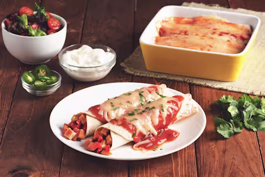 Two enchiladas made with flour tortillas topped with red sauce and cheese filled with Quorn Meatless Vegetarian Turkey Roast.