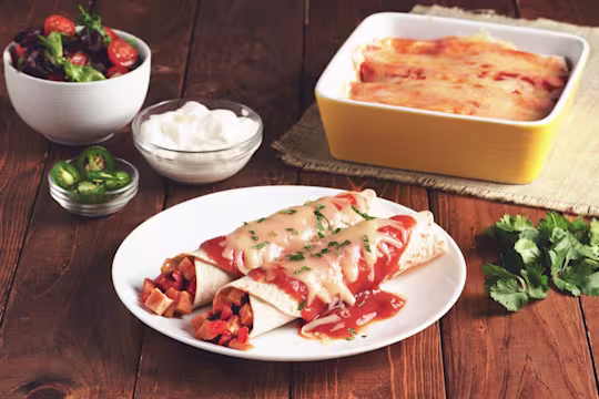 Two enchiladas made with flour tortillas topped with red sauce and cheese filled with Quorn Meatless Vegetarian Turkey Roast.