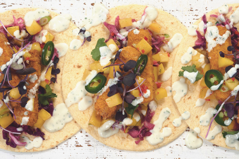 Tacos made with Quorn Vegan Fishless Fingers, jalapenos, diced mango and red cabbage served on tortillas drizzled with yoghurt