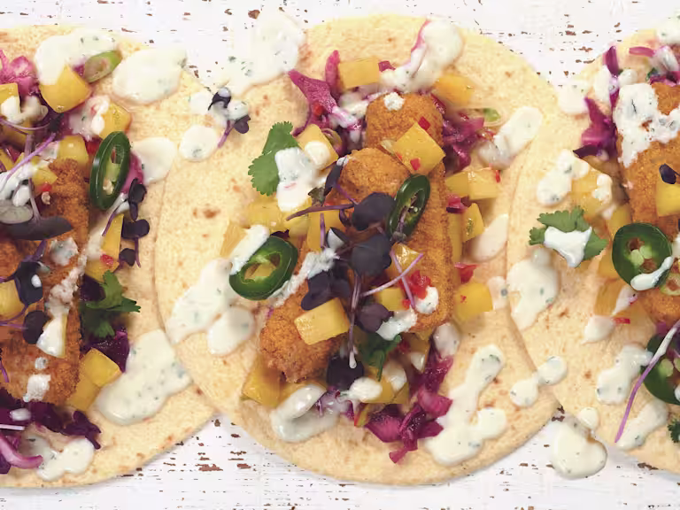 Tacos made with Quorn Vegan Fishless Fingers, jalapenos, diced mango and red cabbage served on tortillas drizzled with yoghurt