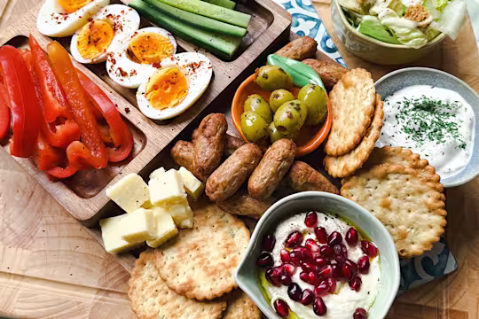 A Summer Snack Plate with Quorn Cocktail Sausages, cheese, crackers, boiled eggs, peppers, cucumber, olives, tzatziki and hummus.